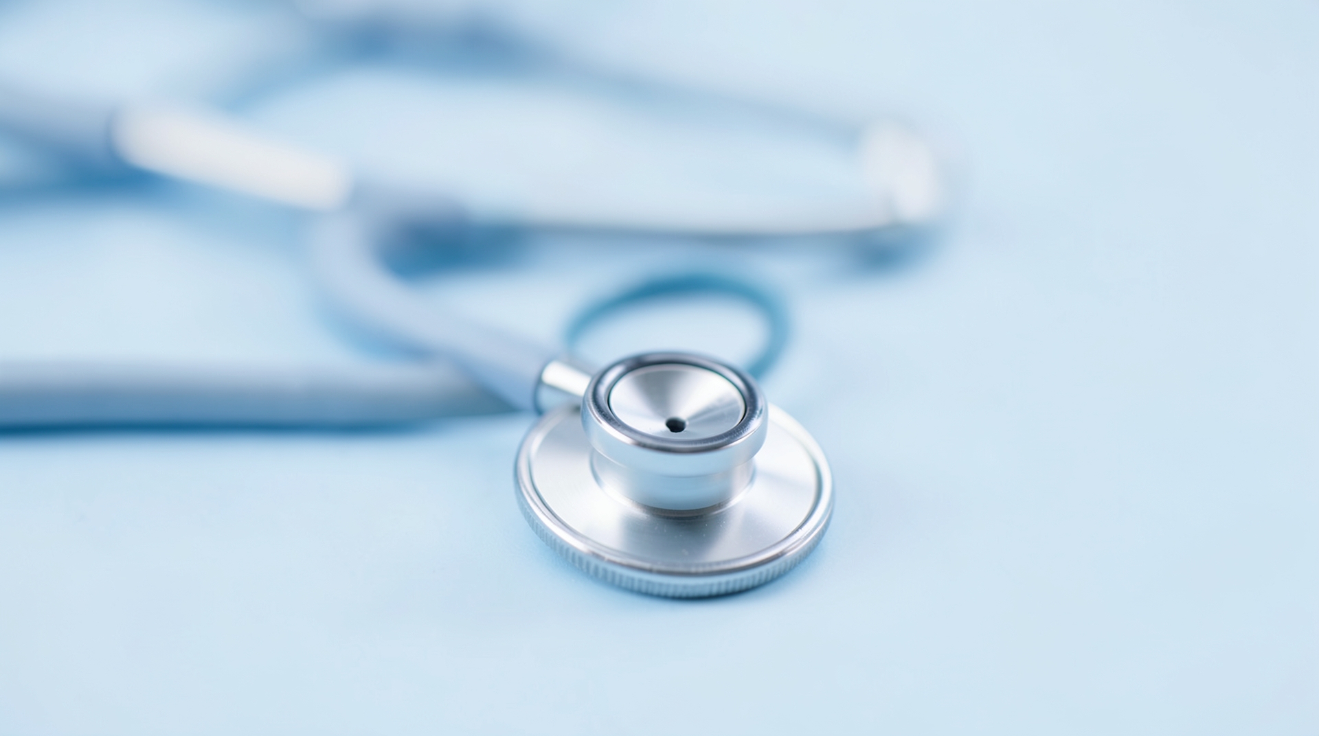 A close-up of a stethoscope on a clean light blue background