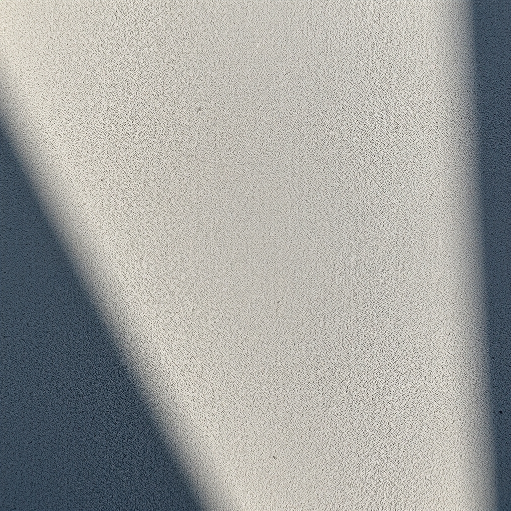 Close-up of rough concrete texture with natural lighting and dramatic shadows.